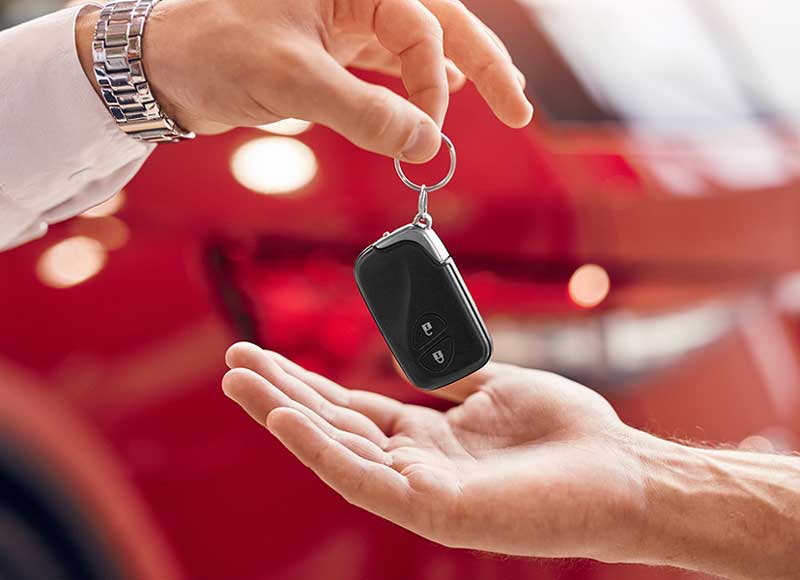 Hand giving a car key to another person